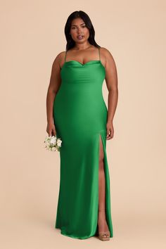 a woman in a green dress with her legs slited up and holding a white flower