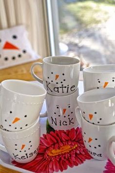 a tray with coffee cups and mugs decorated like snowmen, one has a red flower on it