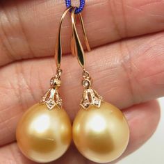 "Lovely in house designed dangle earrings, made of 14k solid yellow gold with 14 natural mine small accent diamonds & an organic natural GOLDEN, south sea cultured pearls from Australia. Each of the HUGE 'Find Drop' pearl exhibits excellent high luster and thicker nacre. The pearls also possesses a silky smooth surface with just a minimal natural blemish. Style: Hook. Metal Purity: 14k Solid Yellow Gold. Genuine Diamond: 14 pcs / 0.059 ctw. Earring approx. Length (including pearl): 1.4 inche Pear-shaped Yellow Gold Earrings With Ear Wire, Yellow Gold Pear-shaped Earrings With Ear Wire, 14k Yellow Gold Dangle Pearl Earrings, South Sea Pearls Earrings, Golden South Sea Pearls, Yellow Gold Earrings, Pearl Types, South Sea Pearls, South Seas