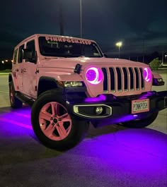 a pink jeep parked in a parking lot with purple lights on it's side