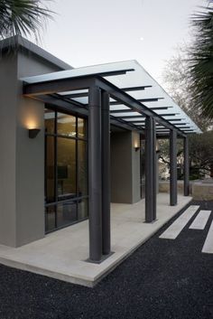 a modern building with metal columns and glass doors on the front entrance to it at dusk