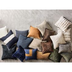 a pile of pillows sitting on top of a bed next to each other in different colors