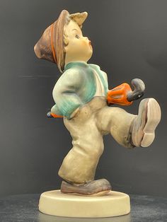 a ceramic figurine of a boy holding a hammer and wearing an orange helmet