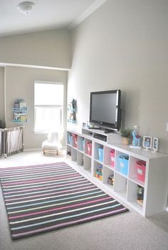 a living room filled with furniture and a flat screen tv on top of a white shelf