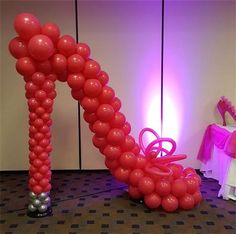 an arch made out of balloons with a high heel shoe on the floor next to it