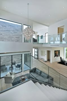 a living room filled with furniture next to a large glass window covered staircase leading up to the second floor