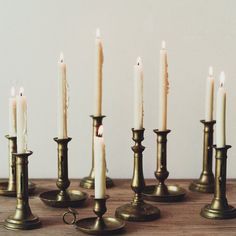 several candles are lined up in rows on a wooden table with one candle lit and the other turned off