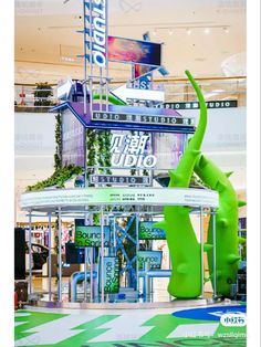 a large green elephant statue sitting in front of a building with signs on it's side