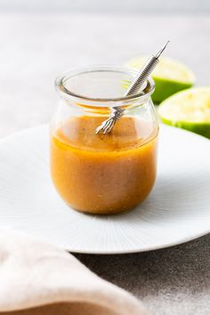 a jar filled with liquid sitting on top of a white plate next to sliced apples