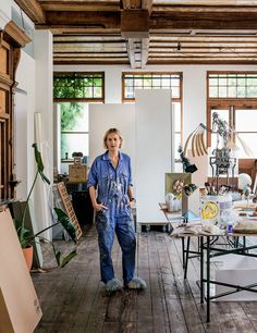 a woman standing in an art studio surrounded by furniture