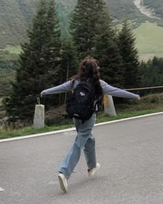 a woman walking down the road with her arms spread out in front of her back