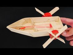 a hand holding a wooden model of a boat with paddles and two oars