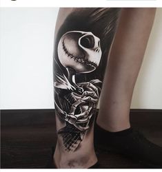 a woman's leg with a skeleton and roses tattoo design on the calf area