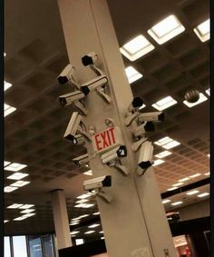 there are many cameras mounted to the ceiling in an office building that has exit signs on it