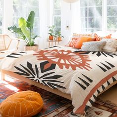 an orange and black bed in a white room with plants on the wall behind it