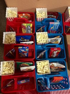 several trays filled with snacks on top of a floor next to a box full of popcorn