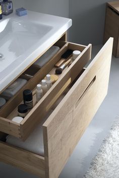 an open drawer in a bathroom next to a sink and counter top with various items inside