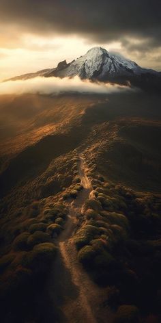 an aerial view of a dirt road leading to a snow covered mountain in the distance