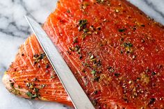 a piece of salmon with seasoning on it next to a knife