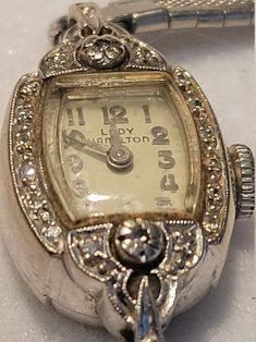 "Vintage \"Lady Hamilton\" 17 Jewel 14K Biggs White Gold Ladie's Wrist Watch, with diamonds.  Admittedly, this needs cleaning up.  Watch runs.  I did not open back to view the mechanism.  Not sure how the back opens, so I devided to just leave it alone.  This was a 25 year service gift for my great aunt, an employee at Callaway Mills in LaGrange, GA.  (It is engraved on the back to her)." Luxury Vintage Silver Watch Bands, Luxury Antique Women's Diamond Watch, Luxury Vintage Jewelry And Watches With Brilliant Cut, Luxury Antique Platinum Watches, Luxury Vintage Diamond Watch For Wedding, Luxury Vintage Watch Bands For Anniversary, Luxury Vintage White Gold Diamond Watch, Luxury Antique White Gold Jewelry And Watches, Vintage Luxury Diamond Watch With Diamond Hour Markers