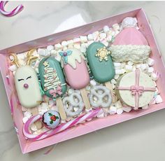 an assortment of decorated cookies in a pink box