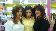 three women standing next to each other in front of a store