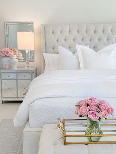 a white bed with pink roses in a vase