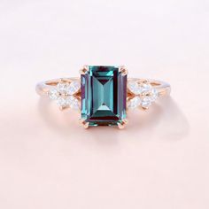 an emerald and diamond ring on a pink background