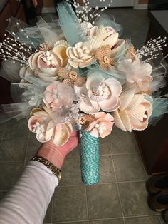 a person holding a bouquet with seashells on it