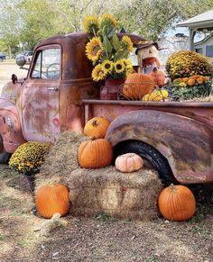 an old truck with pumpkins and sunflowers in the bed