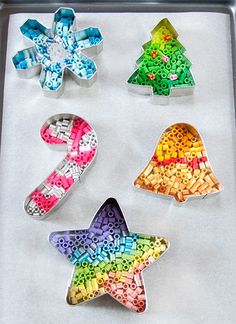 four cookie tins shaped like christmas trees on a baking sheet with candy in them