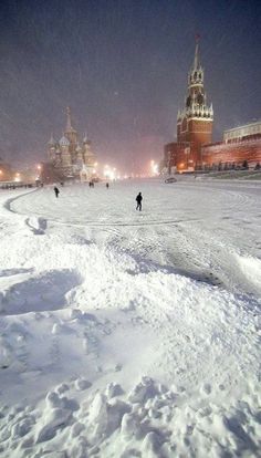 people are walking in the snow near some buildings