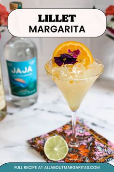 an orange slice is garnished with purple flowers in a martini glass on a marble table