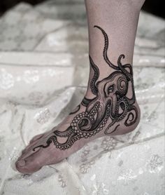 an octopus tattoo is on the foot of a person with black ink and white lace