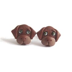 two small brown dogs with big eyes on them'ear studs, one has an eyeball in the shape of a dog