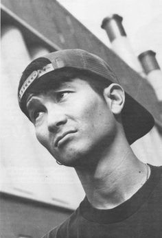 black and white photograph of a man wearing a baseball cap looking up at the sky