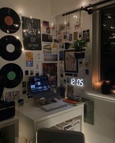 a laptop computer sitting on top of a desk next to a wall covered in records