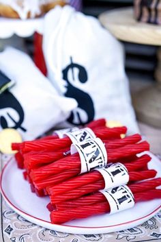 several bundles of red string on a plate next to some white bags with black letters