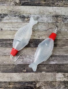 two plastic fish shaped fishing lures sitting on top of a wooden table