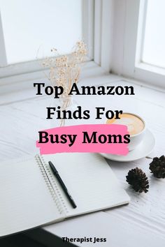 a cup of coffee on top of a desk next to a notebook and pine cones