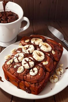 a white plate topped with slices of cake covered in chocolate and banana slices next to a cup of coffee