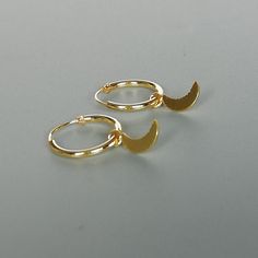 A PAIR of sterling silver hoops dipped in gold. Comes with a tiny crescent moon charm. The charm is multipurpose and can be used with a neck or bracelet chain too. Dimension: Hoop- 12x1 mm Charm- 4 x 9mm Drop length- 18 mm This piece is made of 925 hypoallergenic sterling silver. All my pieces are sent in a gift box. I can include a personal message from you if needed. You are welcome to contact me at... bhavnakwintra1956@gmail.com More hoops: https://www.etsy.com/your/shops/TheSilverGame/tools/ Celestial Small Hoop Huggie Earrings, Adjustable Moon Charm Hoop Earrings, Moon Charm Hoop Earrings In Celestial Style, Adjustable Hoop Earrings With Moon Charm, Celestial Hoop Earrings With Moon Charm, Celestial Round Hoop Earrings With Moon Charm, Dainty Huggie Earrings With Moon Charm, Dainty Dangle Hoop Earrings With Moon Charm, Moon Charm Hoop Earrings For Gift