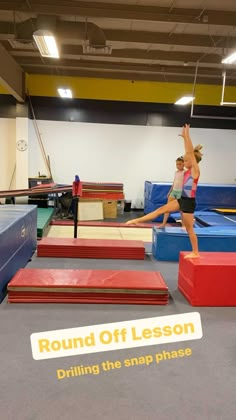 a woman is doing tricks on the trampoline in an indoor gymnastics facility while another girl watches