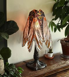 a lamp that is sitting on top of a table next to a potted plant