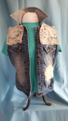 an old jean vest with lace and buttons on the back, worn out to show off