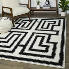 a black and white area rug in a living room with a chair, table and potted plant