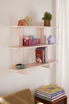 three shelves with books and vases on them in the corner of a living room