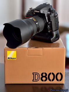 a nikon camera sitting on top of a box with the lens attached to it