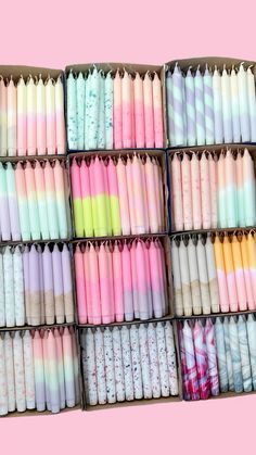 several rows of different colored candles in a box on a pink background with white and black stripes