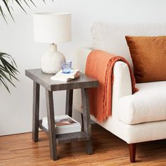 a white couch sitting next to a wooden table on top of a hard wood floor